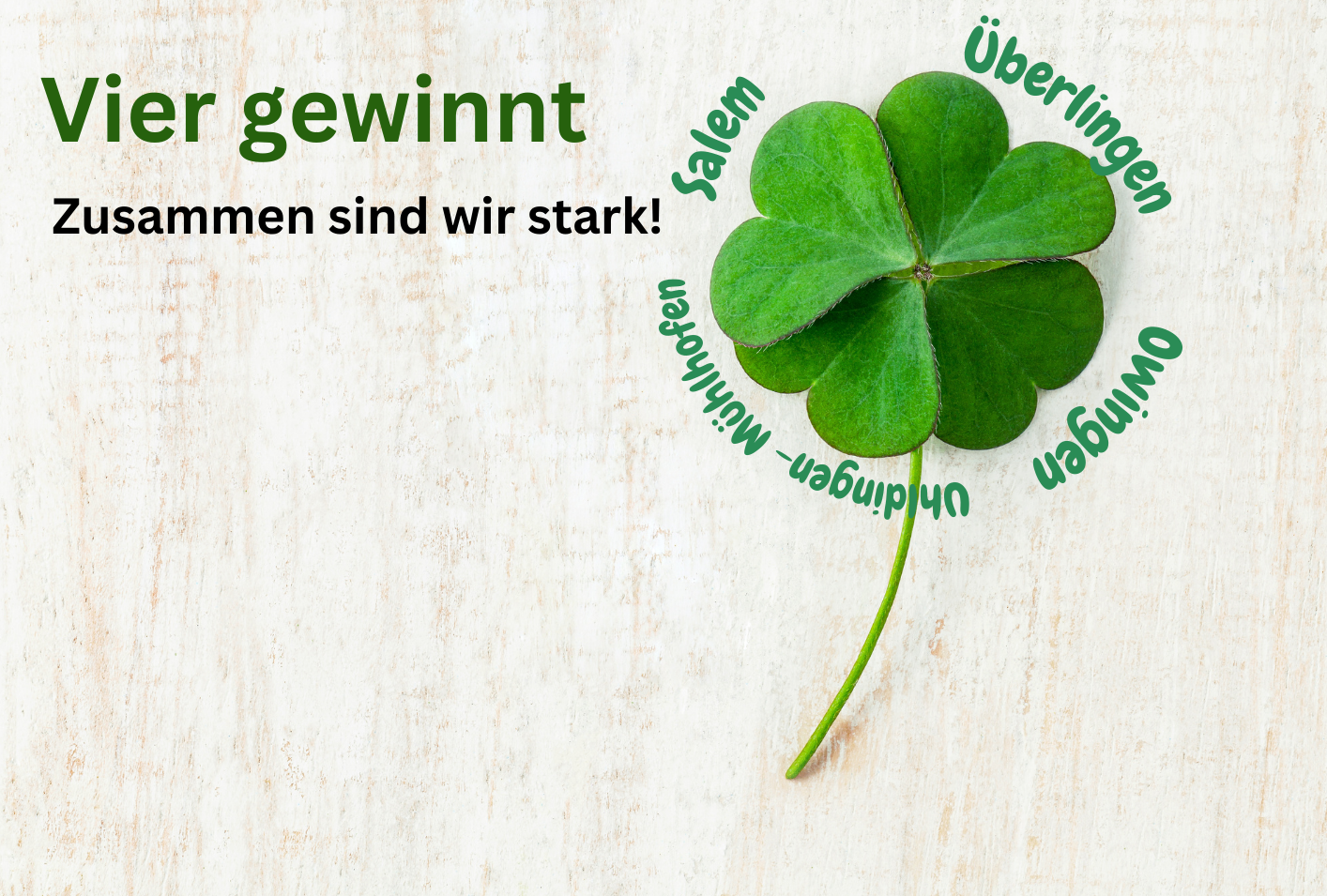 Vierblättriges Kleeblatt mit Städtenamen und deutschem Text auf Holzuntergrund.