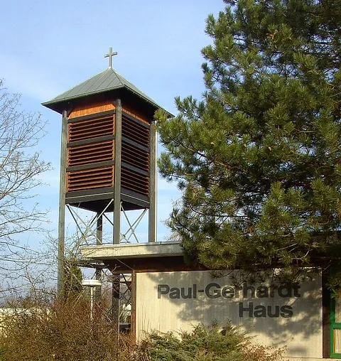 Glockenturm des Paul-Gerhardt-Hauses mit Kreuz und moderner Architektur.