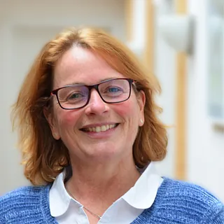 Lächelnde Frau mit Brille und rotblonden Haaren.