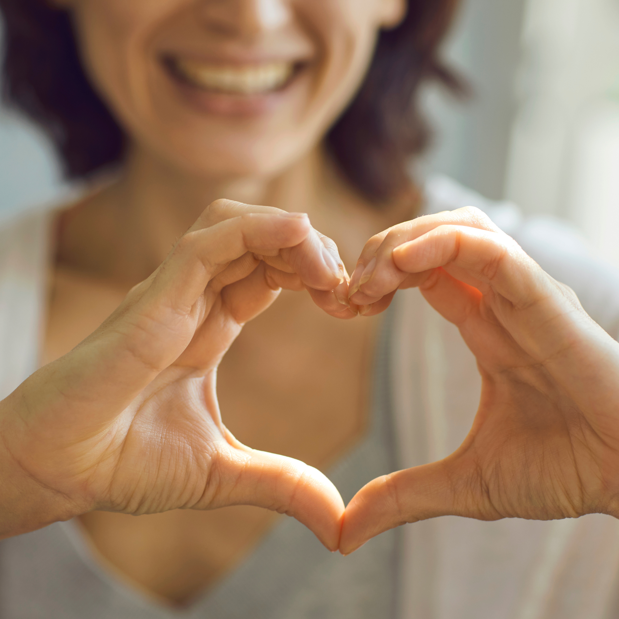  Eine lächelnde Frau formt mit ihren Händen ein Herz.