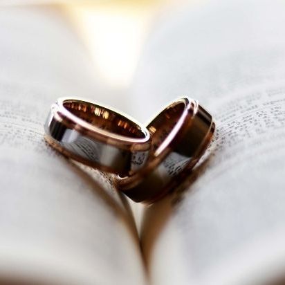 Zwei Eheringe auf einem offenen Buch, die Liebe und Verpflichtung symbolisieren.